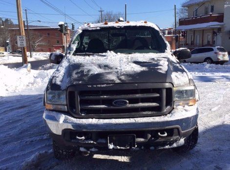 a black ford truck is covered in snow on a snowy street .